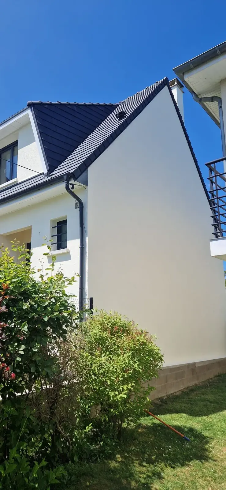 Façade de maison repeinte en blanc, avec un jardin au pied